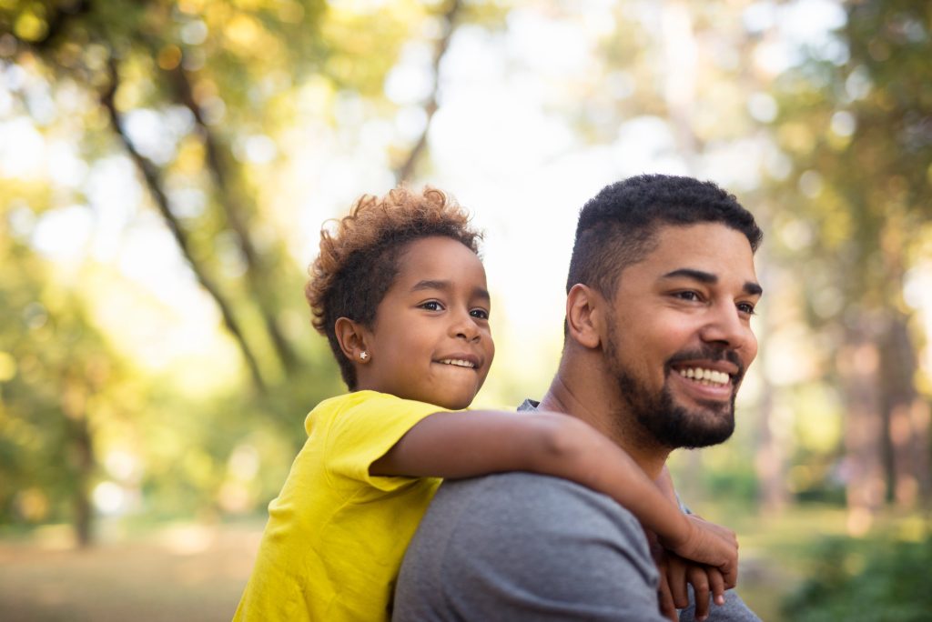 Father carrying child piggyback in a park