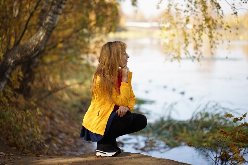 Woman in yellow jacket beside a lake