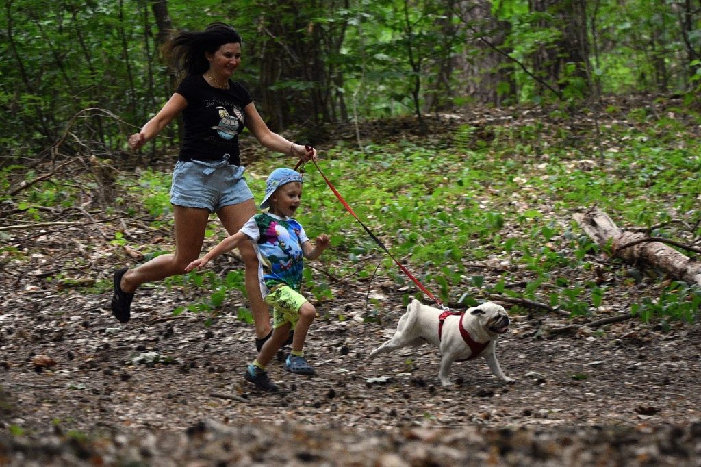 Mother and child running with their dog in the woods